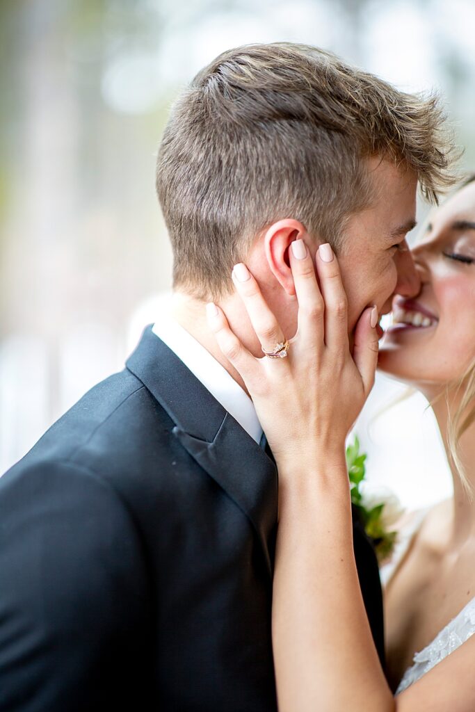 Bride kissing groom and showing ring